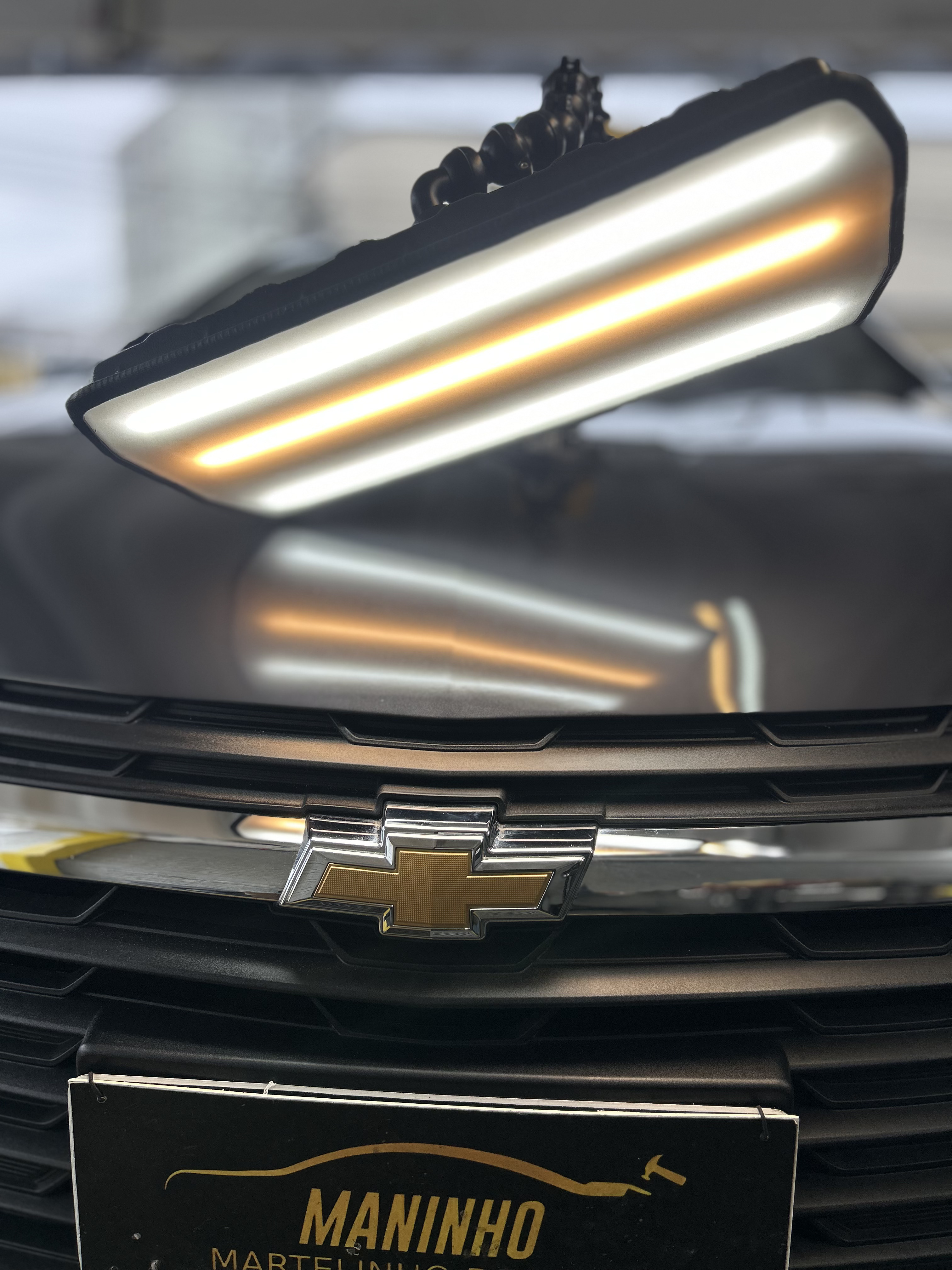 Capô do mesmo Chevrolet preto liso após o reparo